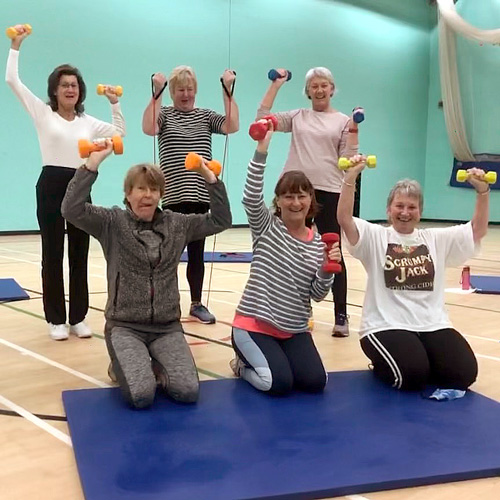 Fit As A Fiddle class members smiling with dumbbells in their hands